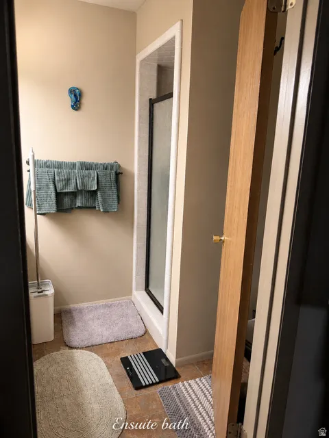 Bathroom featuring a walk-in shower with a black-framed glass door, tile flooring, and a towel bar with multiple rungs