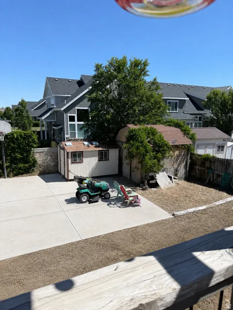 Spacious concrete patio with surrounding landscaping and exterior storage shed