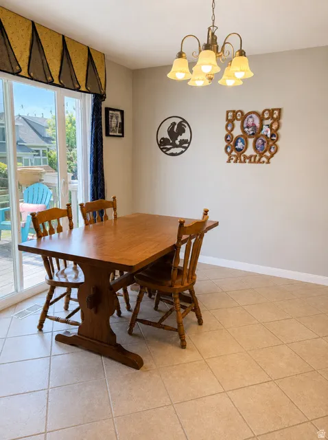 Dining area featuring tile flooring, a brass-finish chandelier, and a sliding glass door to exterior