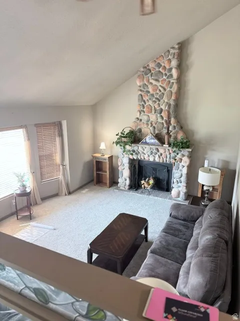 Spacious living area featuring a vaulted ceiling and a floor-to-ceiling stone-faced fireplace with a hearth
