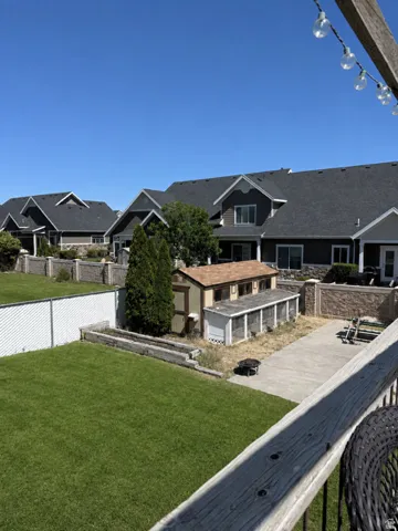 Spacious backyard featuring a manicured lawn, concrete patio, and a dedicated chicken coop structure