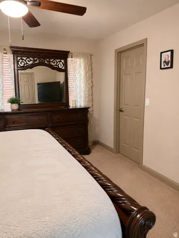 Carpeted bedroom with a ceiling fan