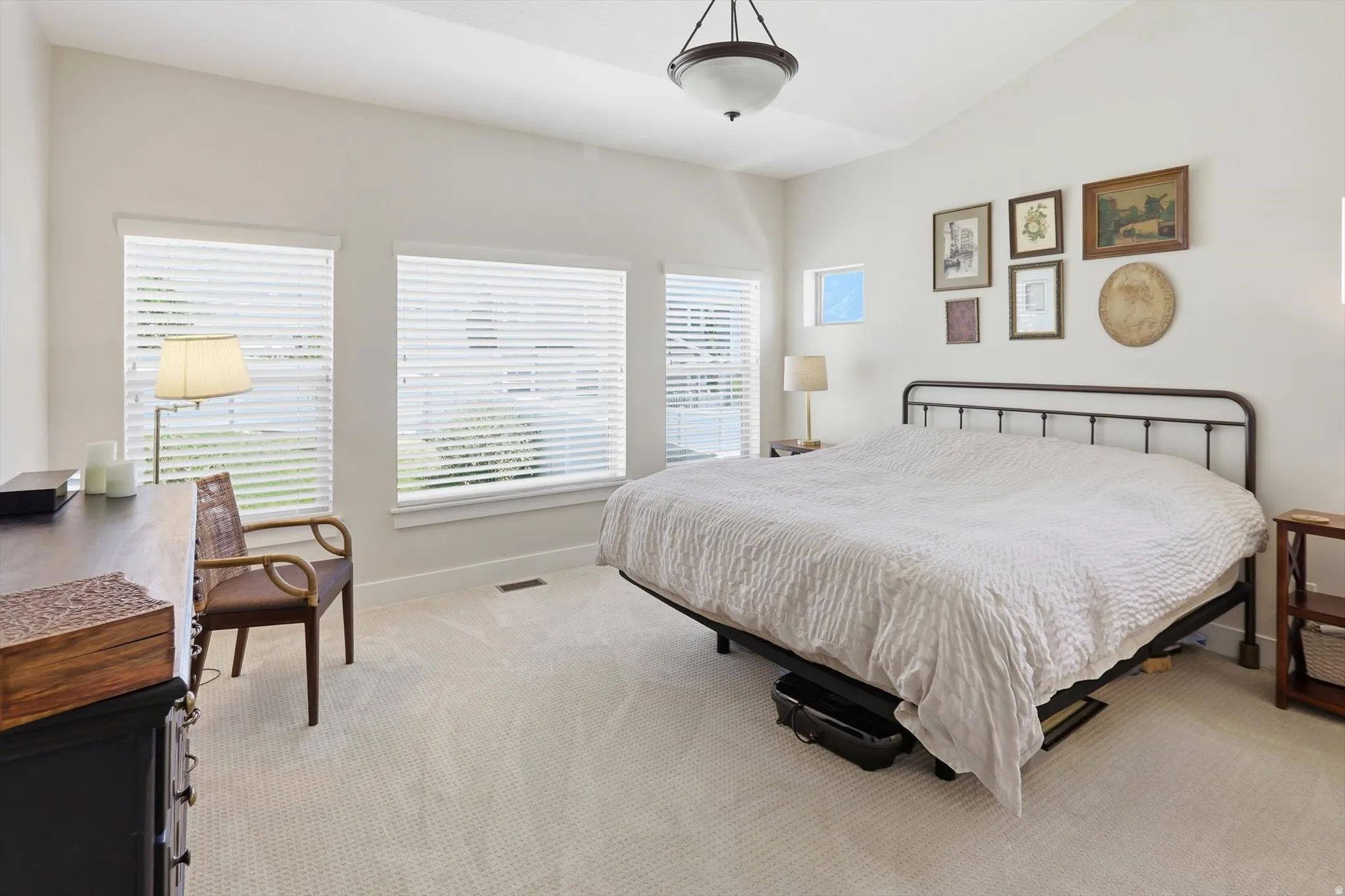 Carpeted bedroom featuring vaulted ceilings, multiple windows with horizontal blinds, and a semi-flush mount ceiling light fixture