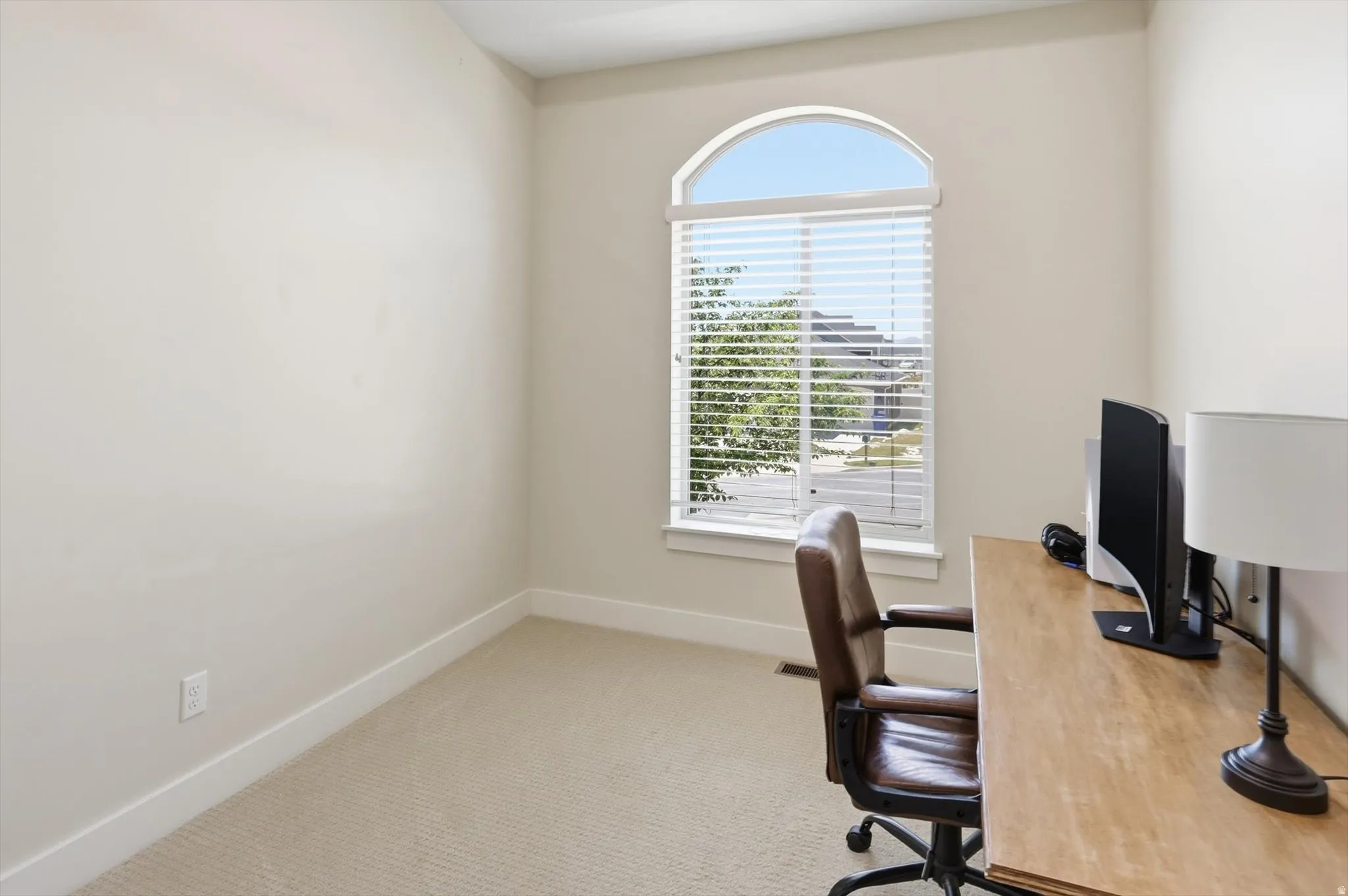 Room featuring a large arched window with blinds, neutral wall paint, and plush carpeting