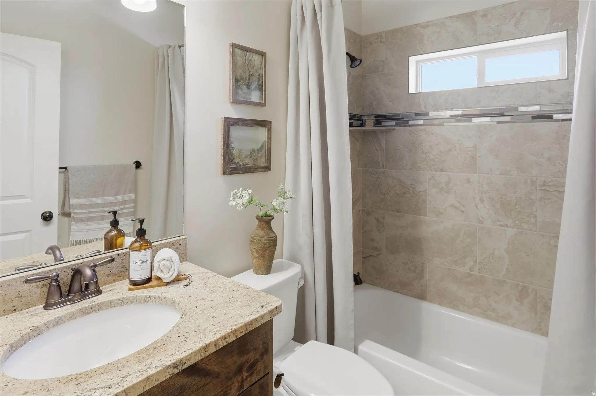 Bathroom featuring a white vanity with granite-look countertop, oval undermount sink, and bronze-finish faucet