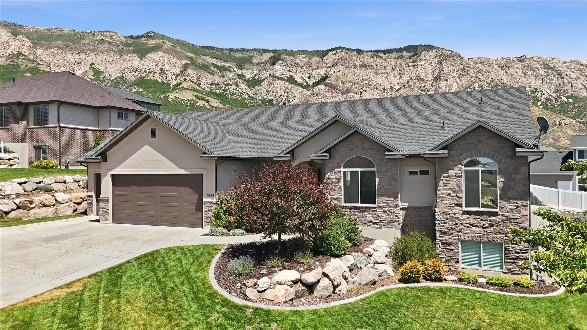 Contemporary residence featuring a split-level design with a prominent stone facade and stucco accents