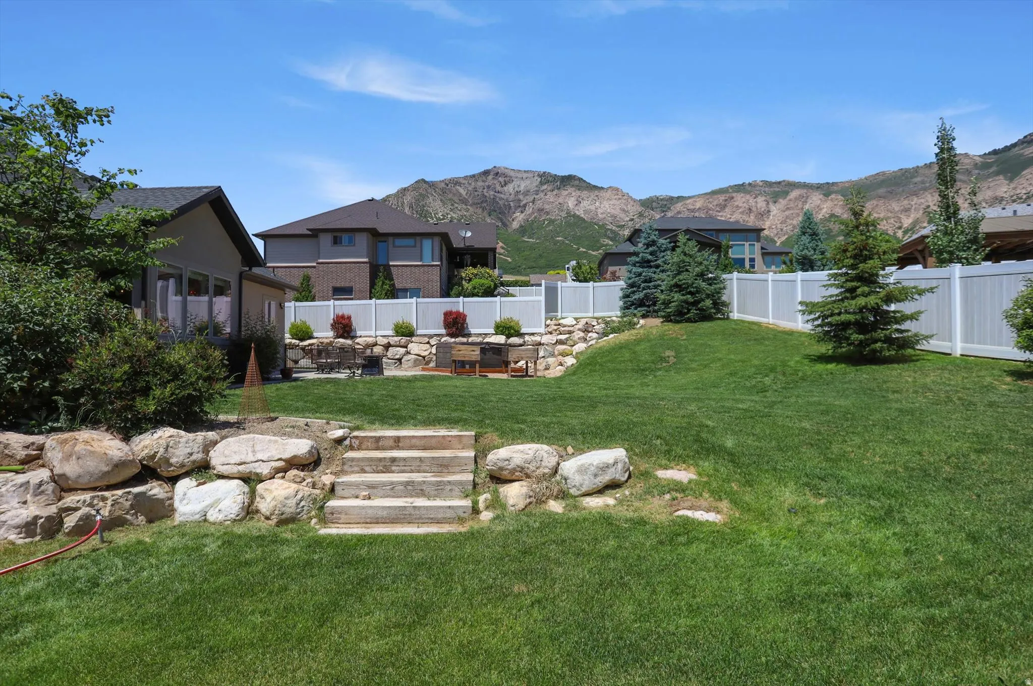 Terraced backyard featuring a stone retaining wall, natural rock landscaping, and a manicured lawn
