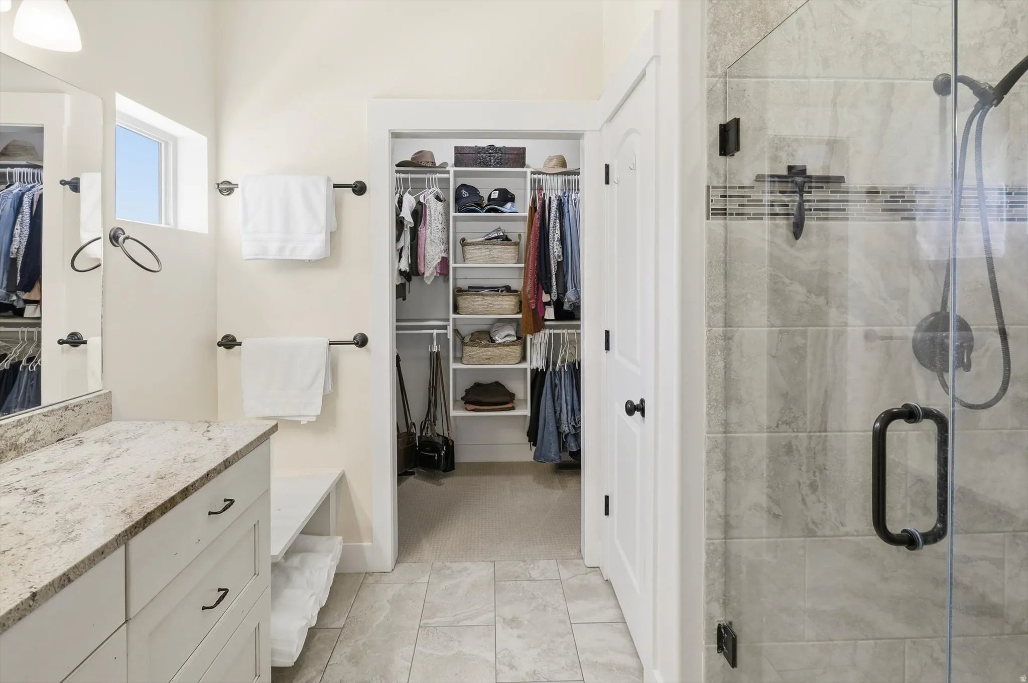 Bathroom with light-toned tiled flooring, white cabinetry, and a stone-finish countertop