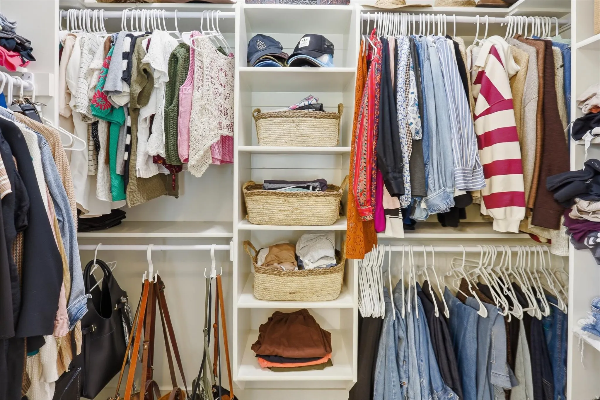 Custom closet system featuring white shelving, multiple hanging rods, and integrated storage compartments