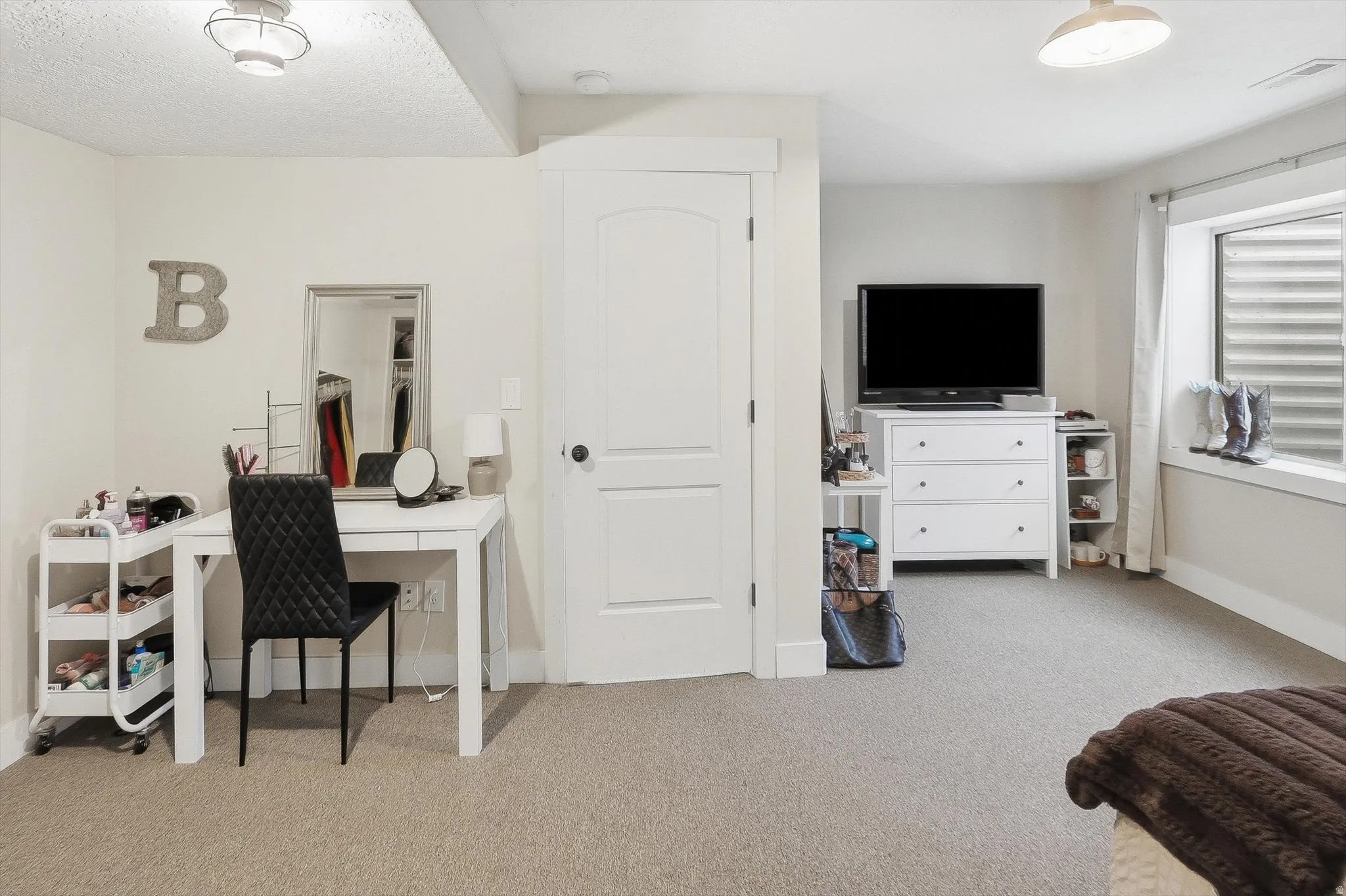 Carpeted interior space featuring a recessed window, a single panel door with white trim, and a flush mount ceiling light
