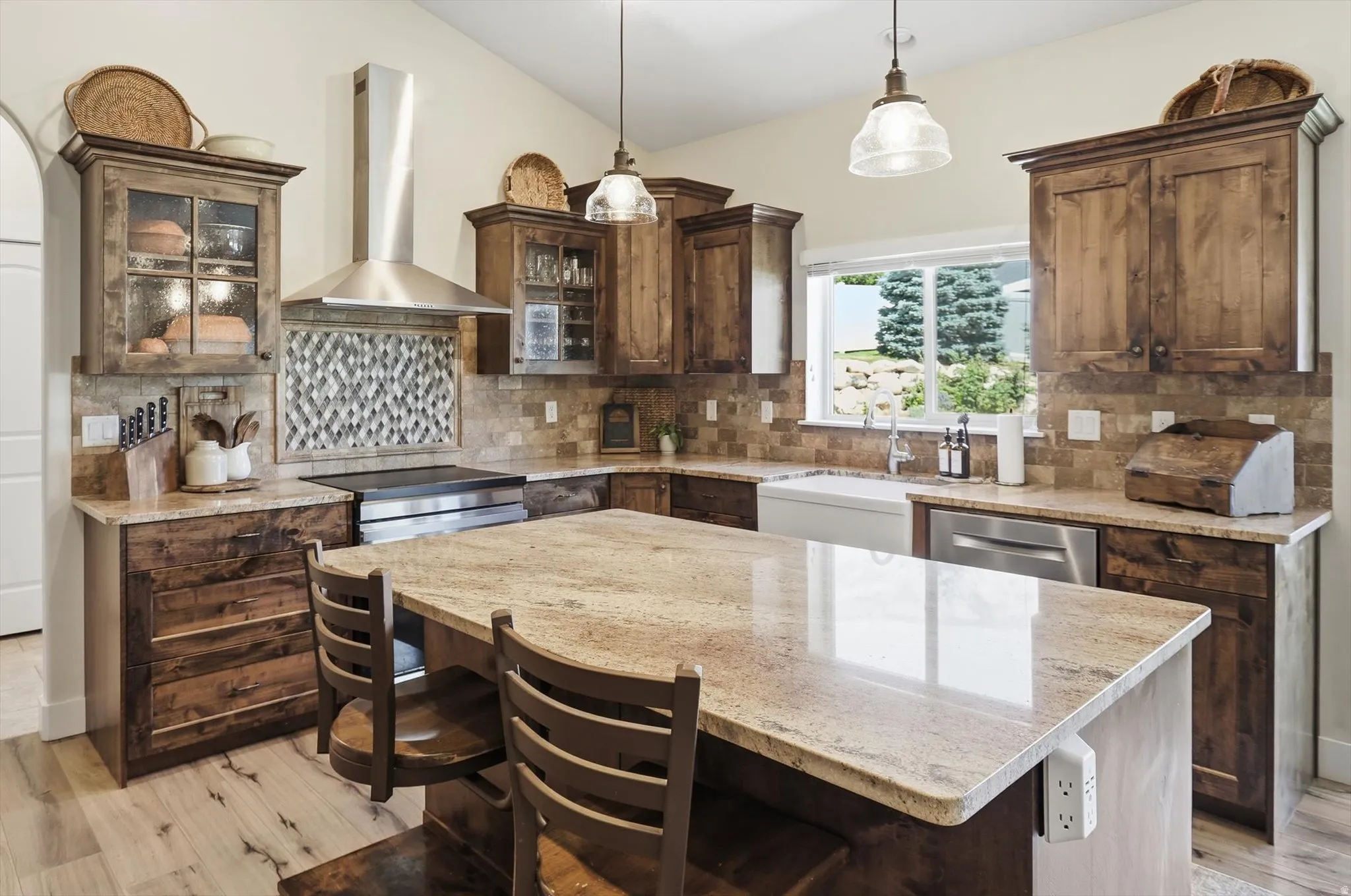 Kitchen featuring wood-finish cabinetry, light-toned granite countertops, a large center island, stainless steel appliances, and a tiled backsplash