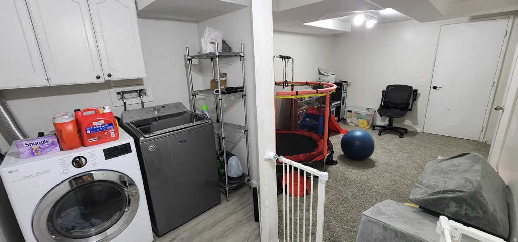 Dedicated laundry area with upper cabinetry and wood-finish flooring