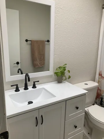 Bathroom featuring white vanity with shaker-style cabinetry, white integrated sink, and matte black fixtures