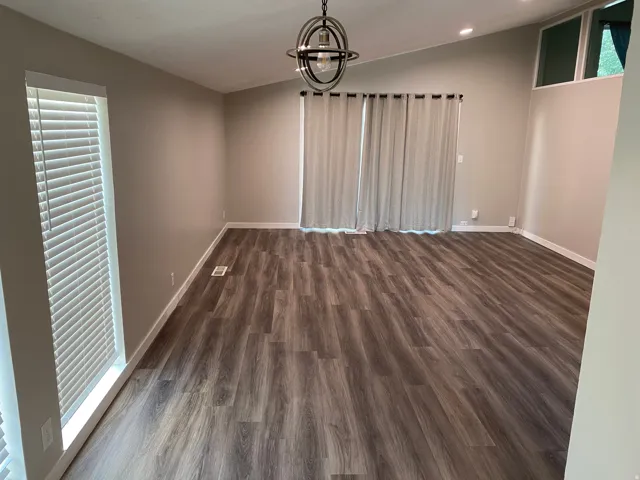 Spacious room featuring vaulted ceilings, wood-finish flooring, a modern orb chandelier, and high transom windows