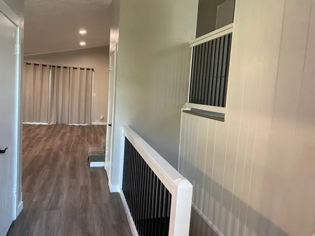 Spacious interior featuring wood-finish flooring, vaulted ceilings with recessed lighting, and a contemporary stair railing with vertical black spindles