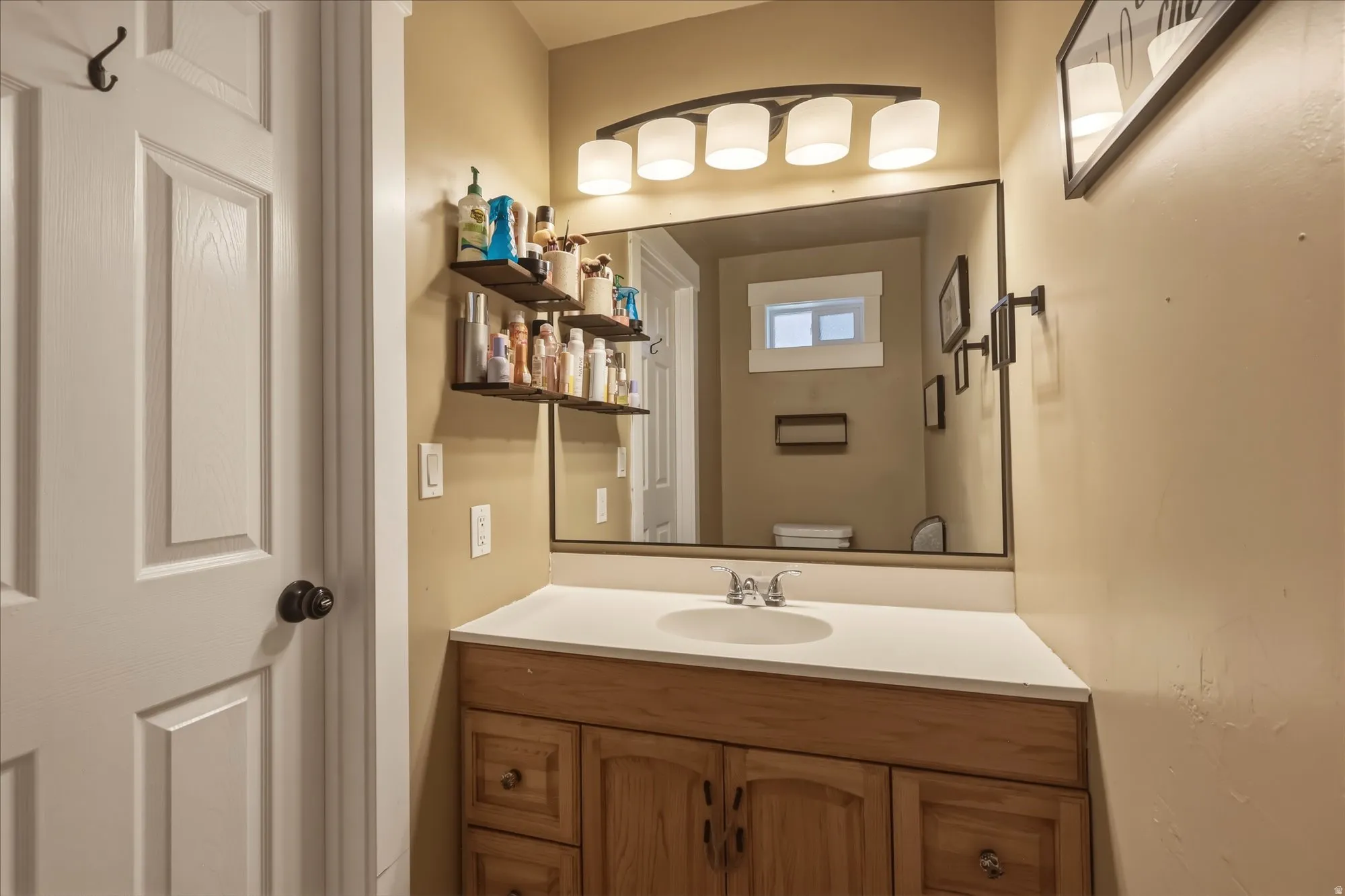 Bathroom vanity with wood-finish cabinetry, a light-colored countertop, and a rectangular sink