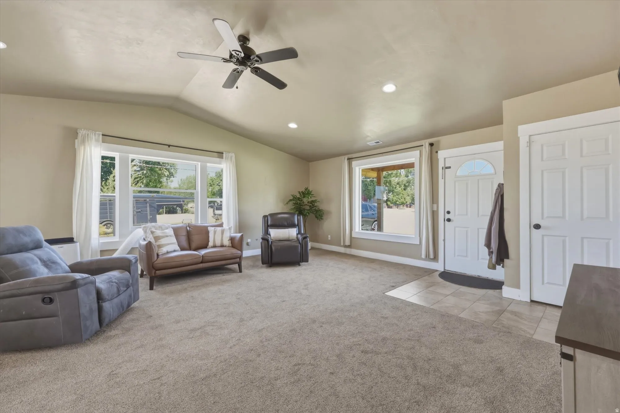 Vaulted ceilings enhance this living area featuring neutral-toned carpeting and recessed lighting