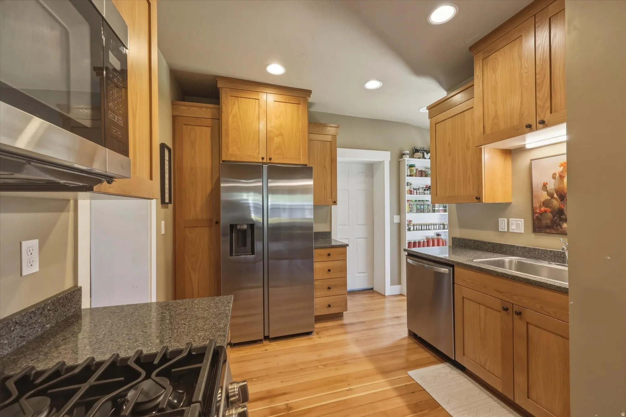 Kitchen featuring wood-finish cabinetry, stainless steel appliances, recessed lighting, and granite countertops