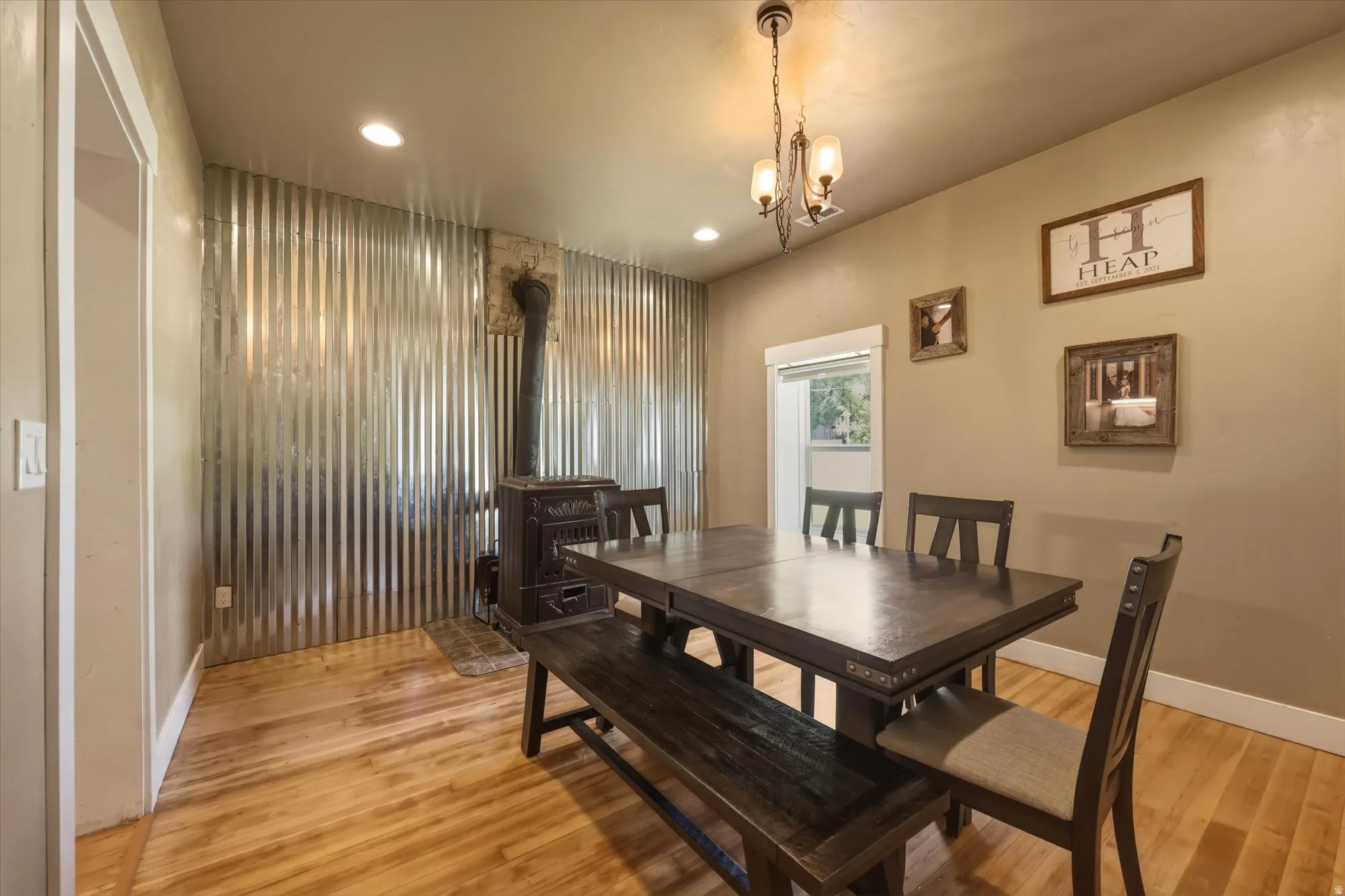 Dining area featuring a corrugated metal accent wall and a classic wood-burning stove