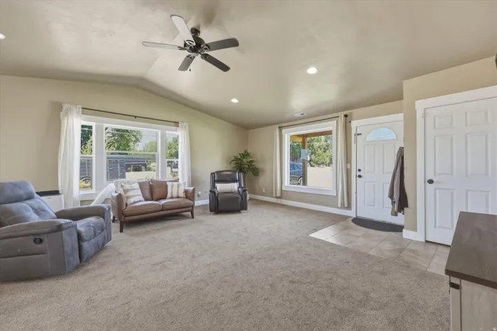 Vaulted ceilings enhance this living area featuring neutral-toned carpeting and recessed lighting