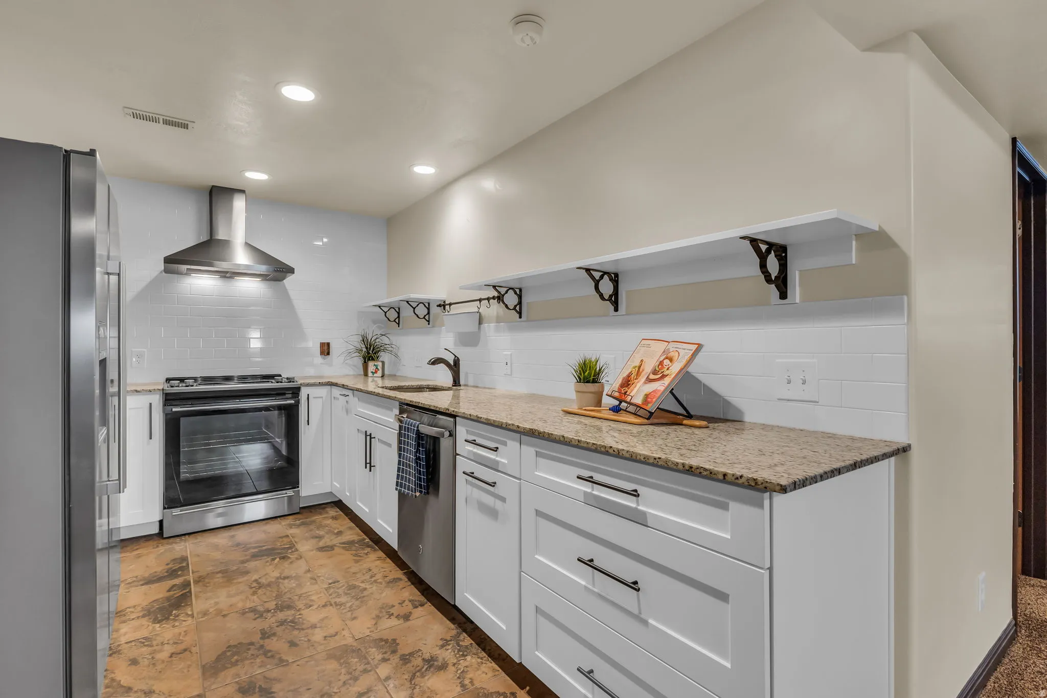 Kitchen featuring white cabinetry, granite countertops, stainless steel appliances, a white subway tile backsplash, and recessed lighting