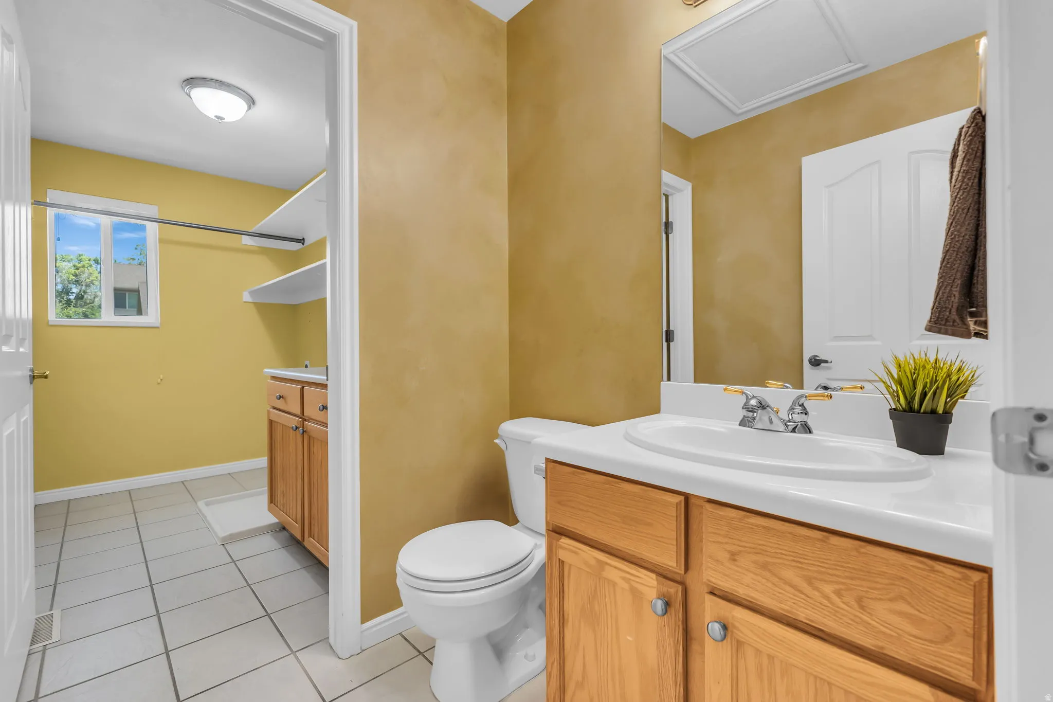 Bathroom and laundry featuring a white ceramic sink, chrome faucet, wood-finish vanity, and a mounted mirror