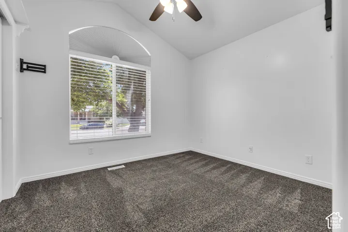 Vaulted ceiling room with an arched window featuring horizontal blinds