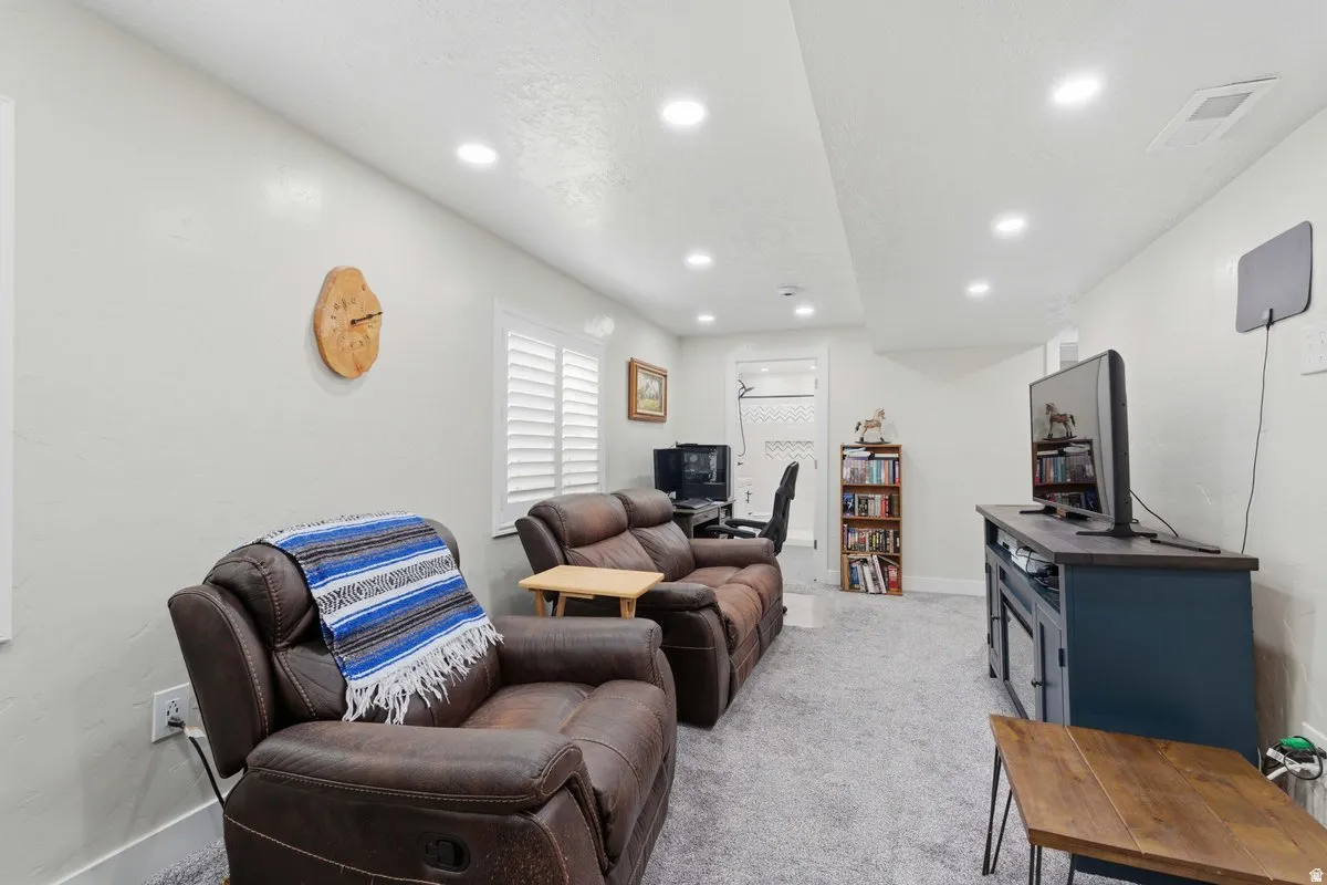 Spacious living area featuring recessed lighting, light gray carpet flooring, white walls, and white plantation shutters