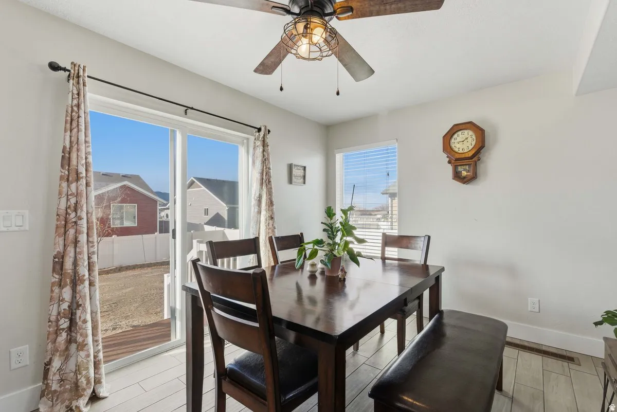 Dining area with sliding glass patio doors, wood-finish flooring, and a ceiling fan with integrated lighting