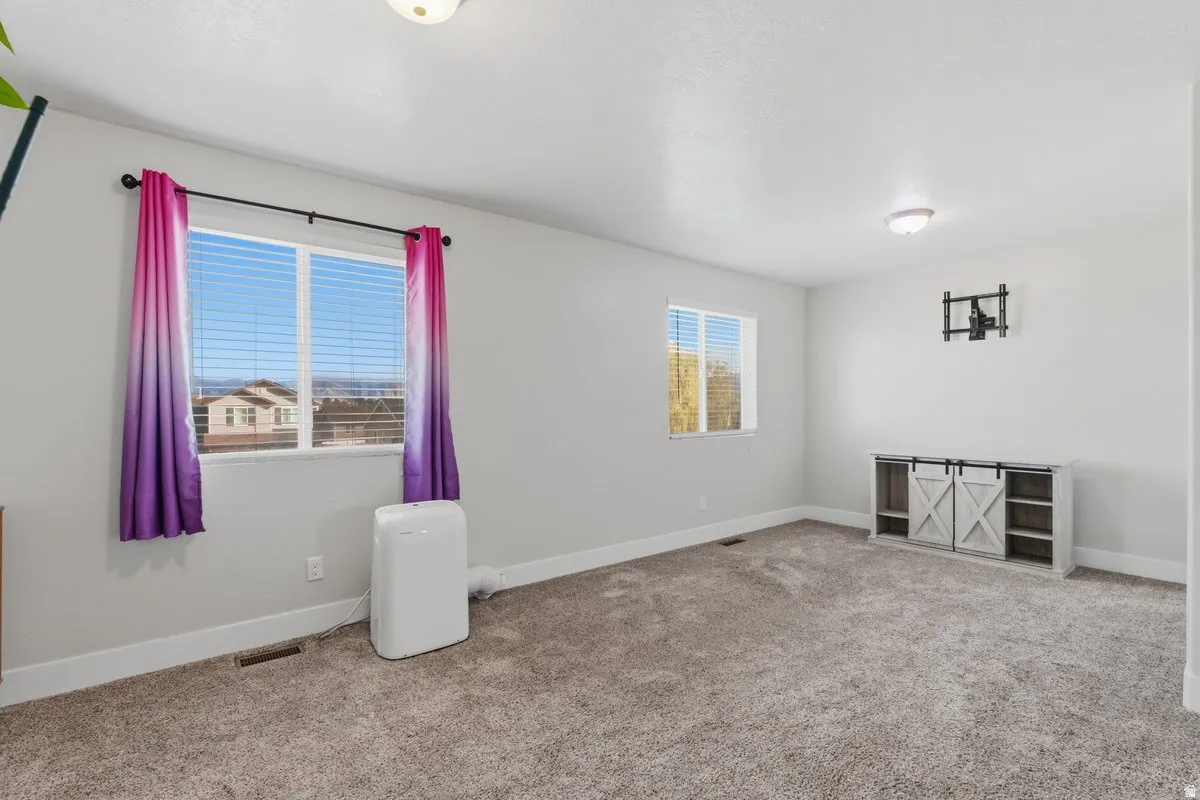 Spacious room featuring neutral carpeting, light gray walls, and white trim