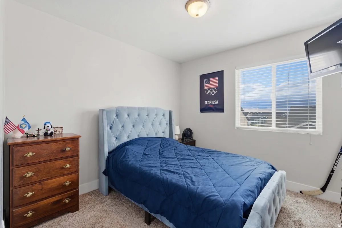 Carpeted room with a ceiling-mounted light fixture and a window featuring horizontal blinds