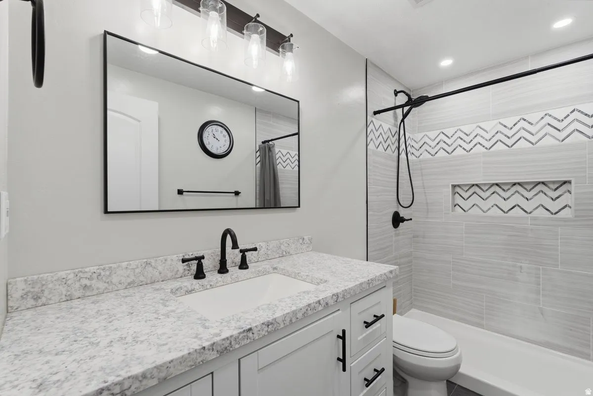 Bathroom featuring a white vanity with a speckled countertop, undermount sink, and matte black fixtures