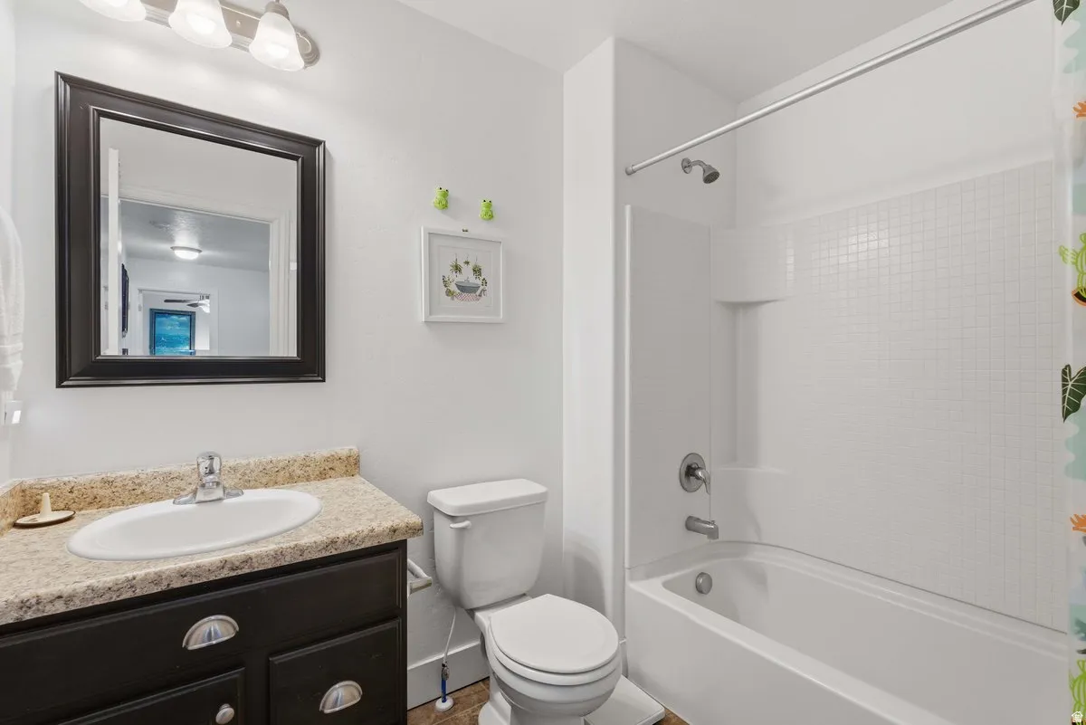 Bathroom featuring a dark wood-finish vanity with a speckled countertop, an undermount sink, and a framed wall mirror
