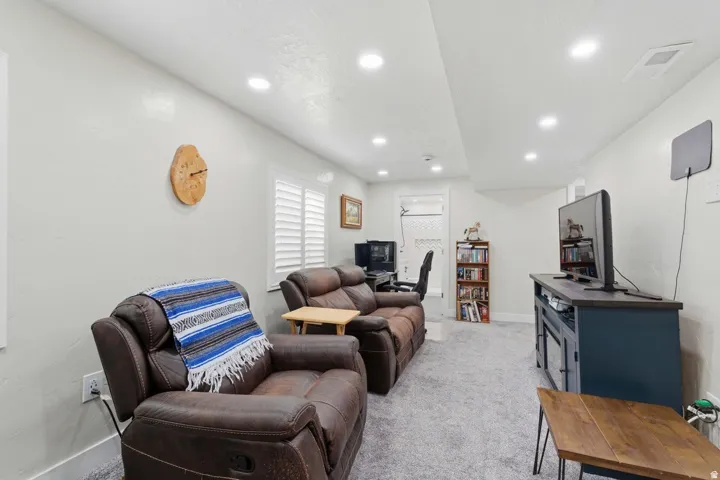 Spacious living area featuring recessed lighting, light gray carpet flooring, white walls, and white plantation shutters