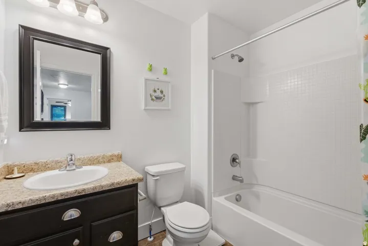 Bathroom featuring a dark wood-finish vanity with a speckled countertop, an undermount sink, and a framed wall mirror