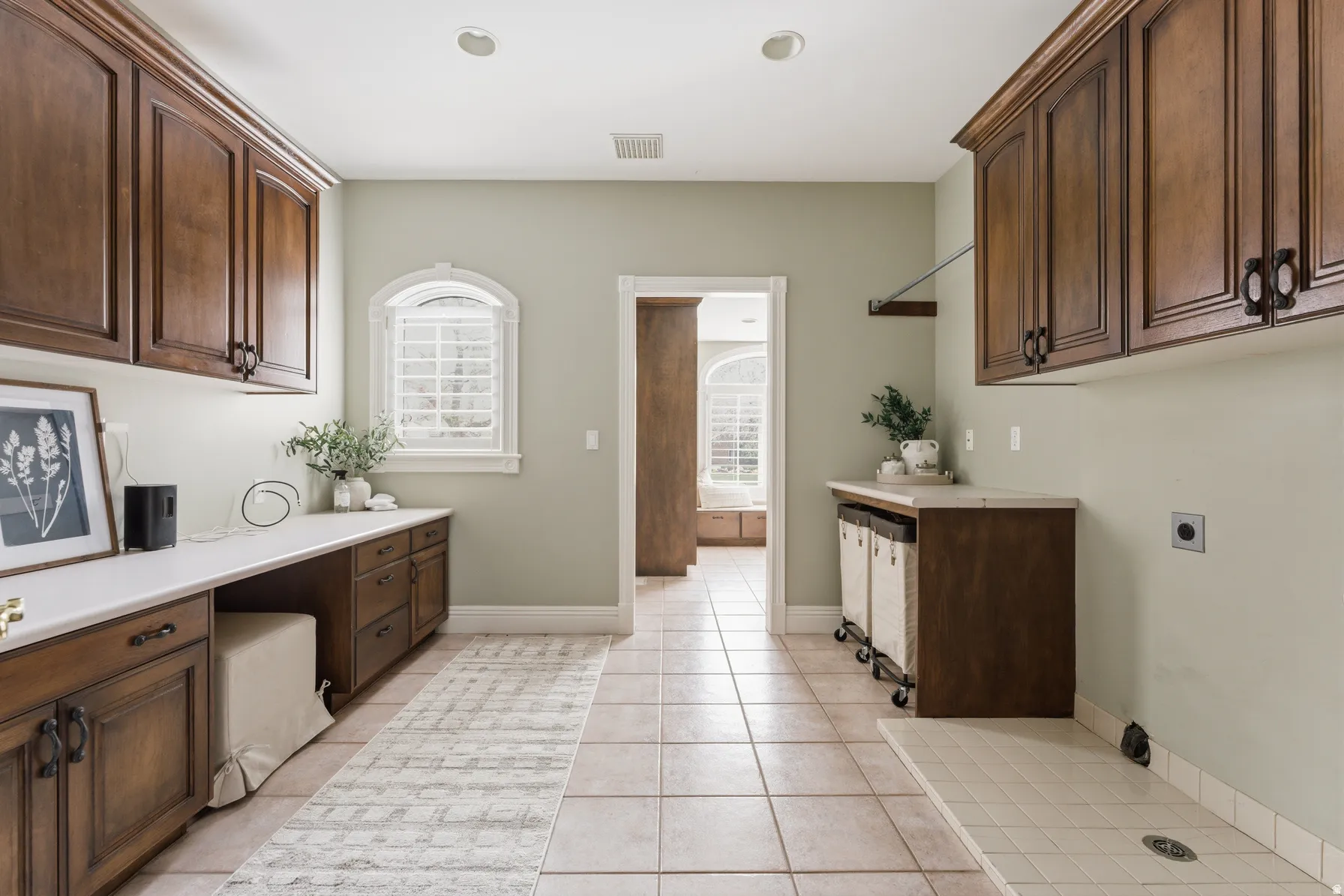 Spacious utility room featuring extensive dark wood cabinetry, light countertops, and tile flooring