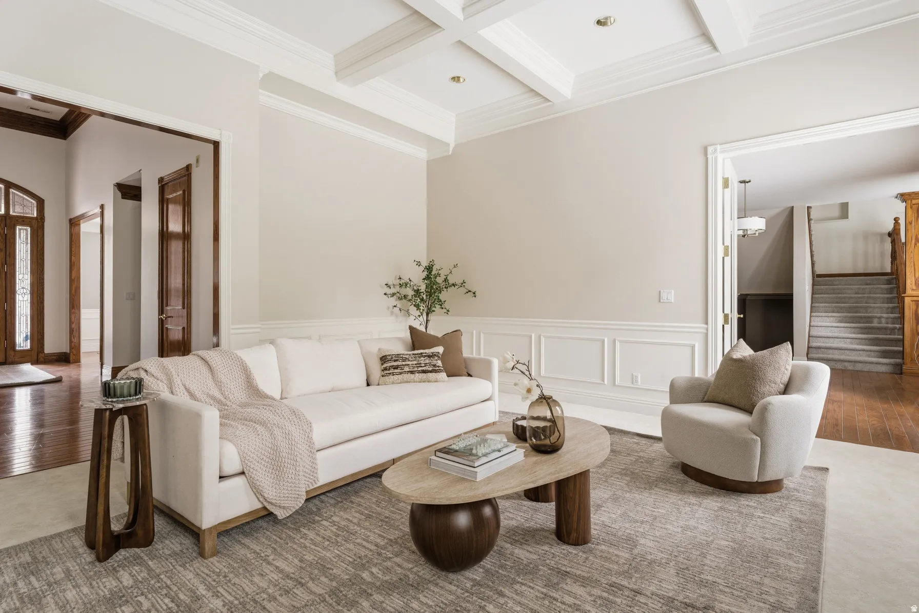 Formal living area featuring a coffered ceiling, elegant crown molding, and wainscoting