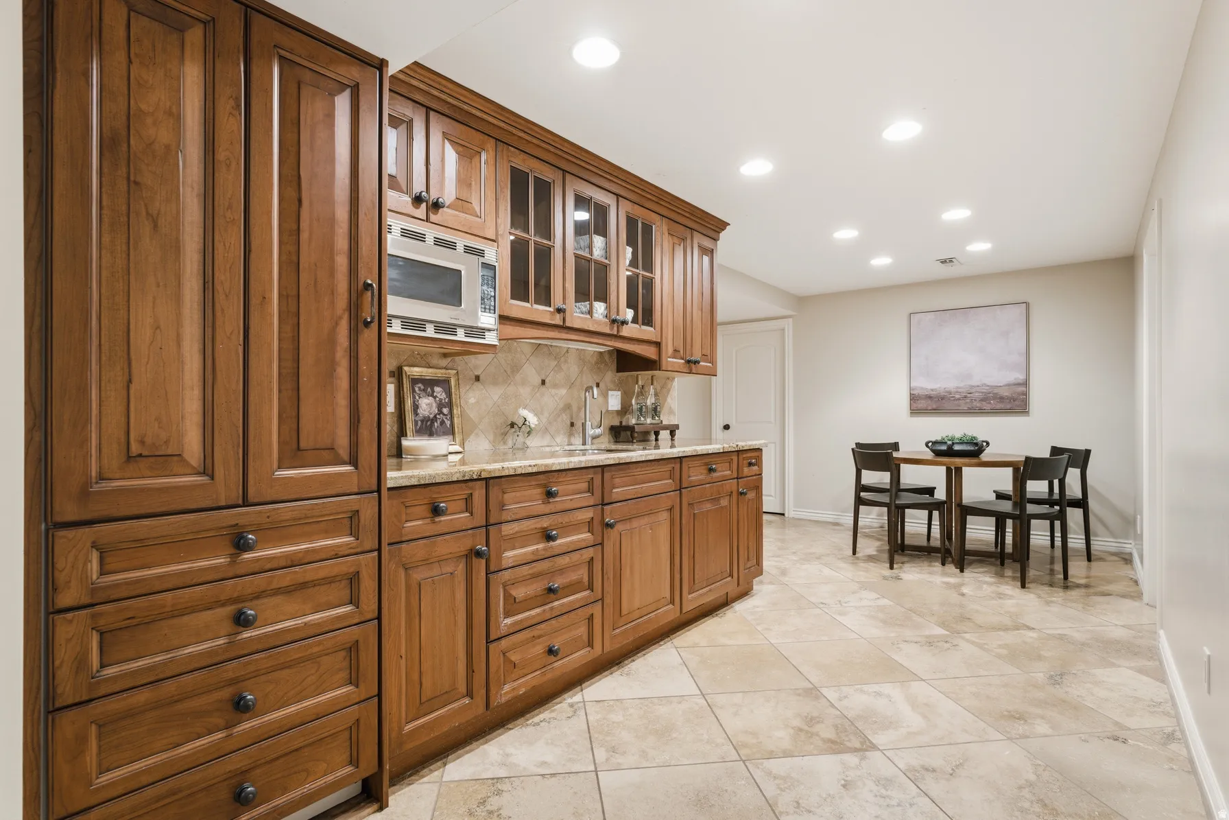 Built-in cabinetry with glass-front uppers and ample storage, stone tile backsplash, and recessed lighting
