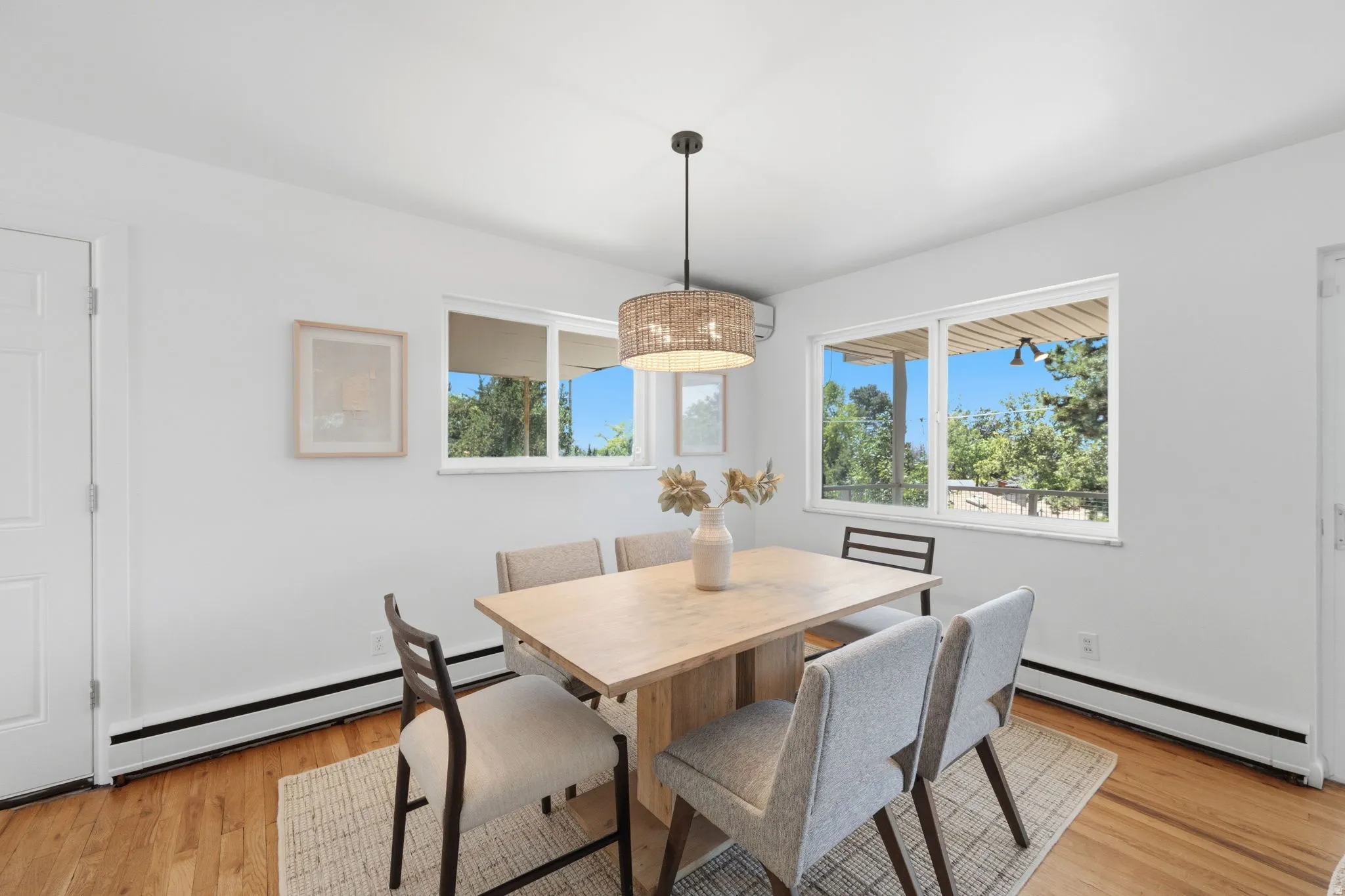 Dining area featuring wood-finish flooring, white walls, and a woven pendant light fixture