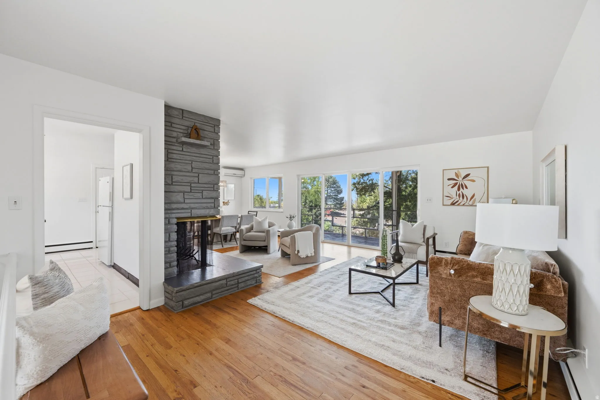 Spacious living area featuring hardwood flooring, a stone-clad fireplace, and double sliding glass doors leading to an outdoor space