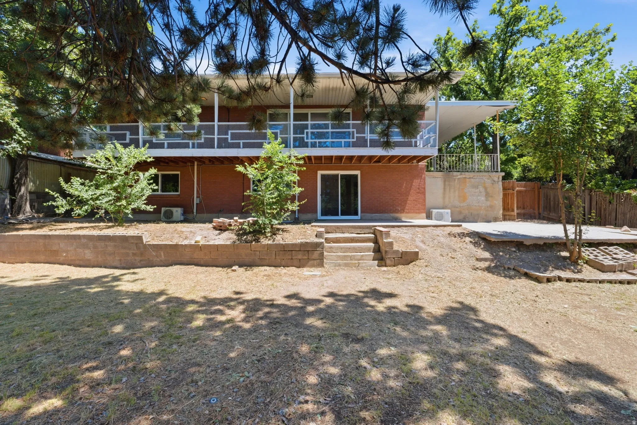 Back of house featuring a brick lower level and an upper-level balcony with white geometric railings