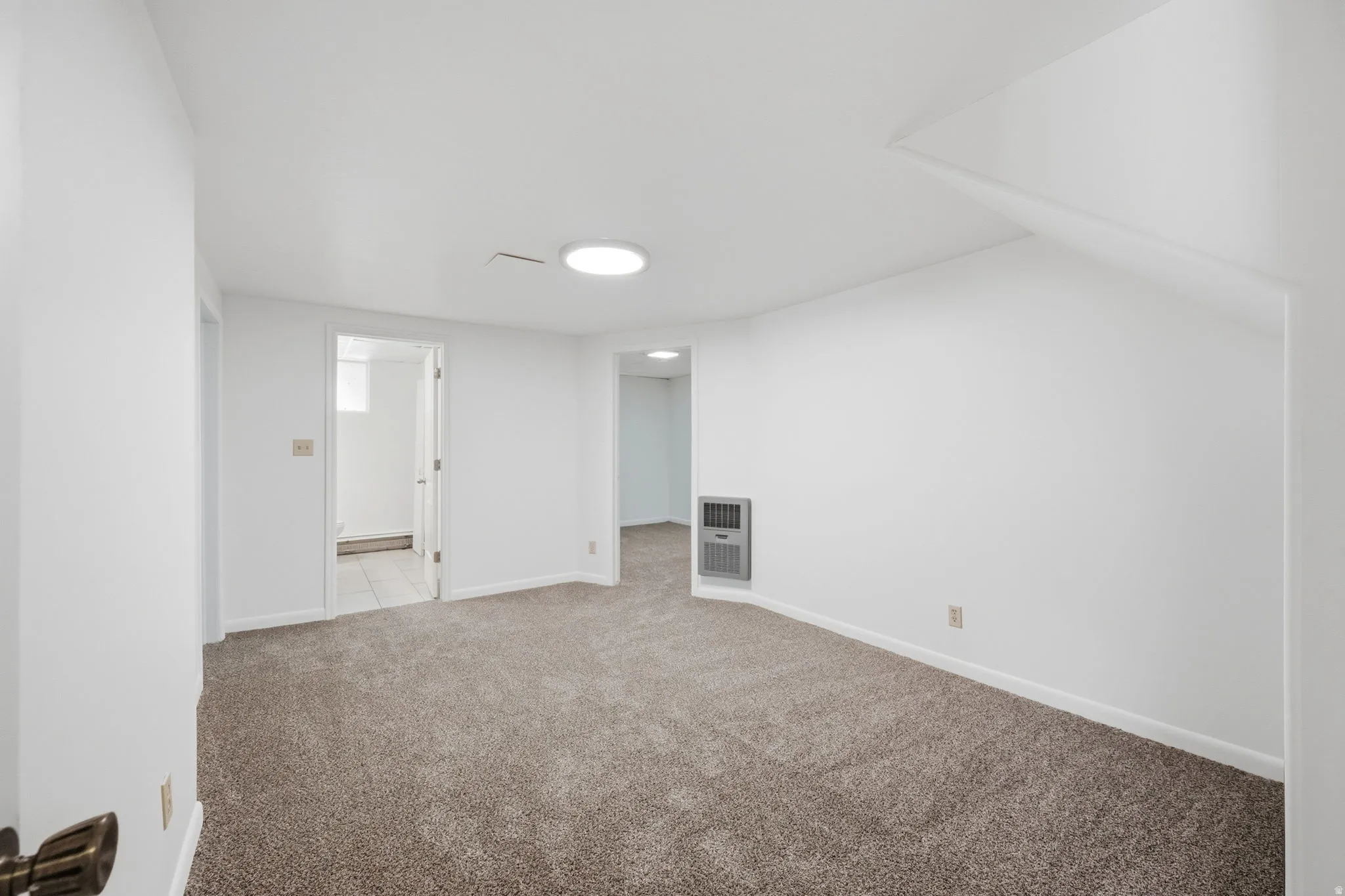Spacious room featuring neutral carpeting, white walls, and bright overhead lighting