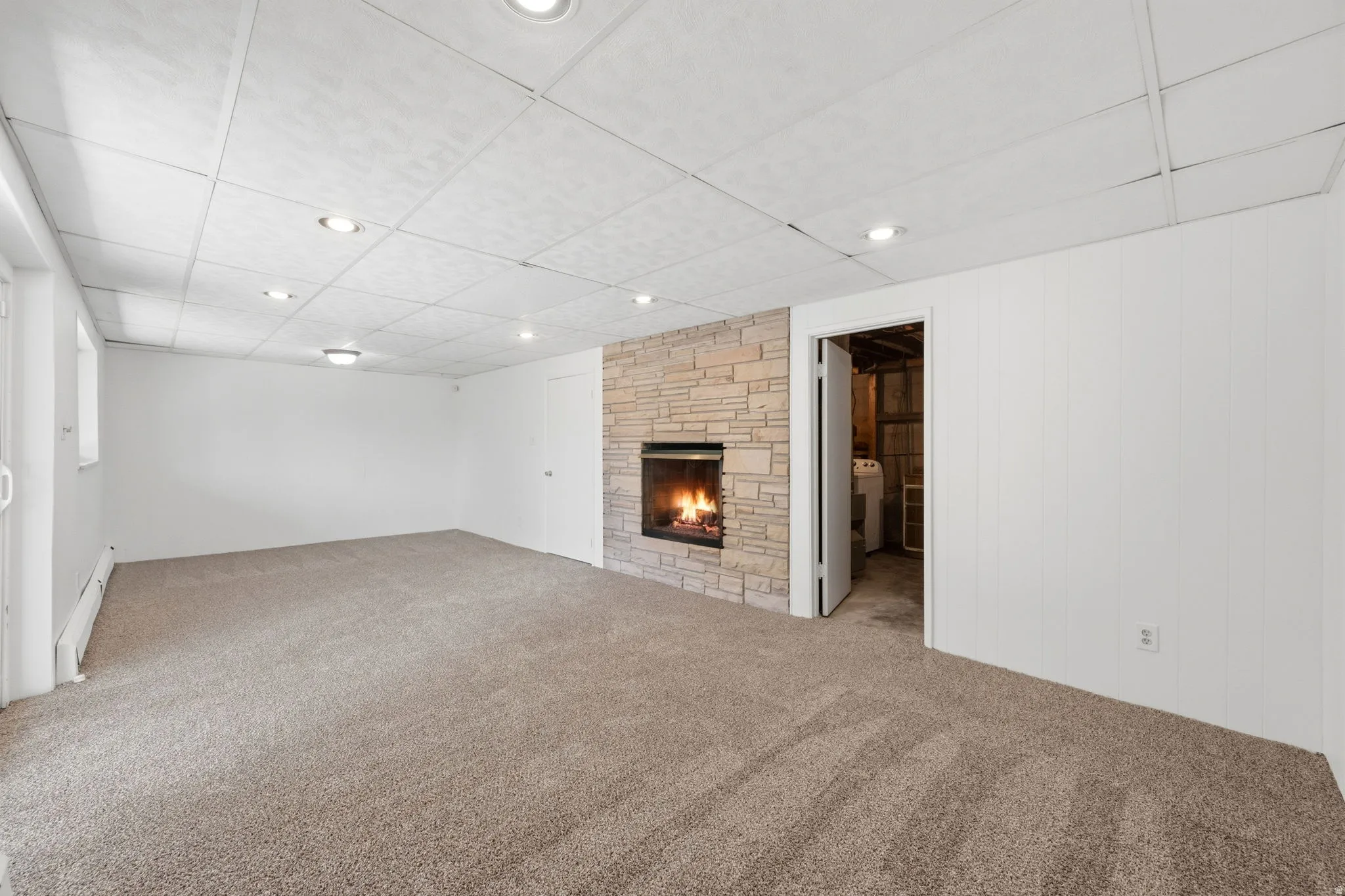 Spacious room featuring a stacked stone fireplace with a black firebox, recessed lighting, and soft carpet flooring