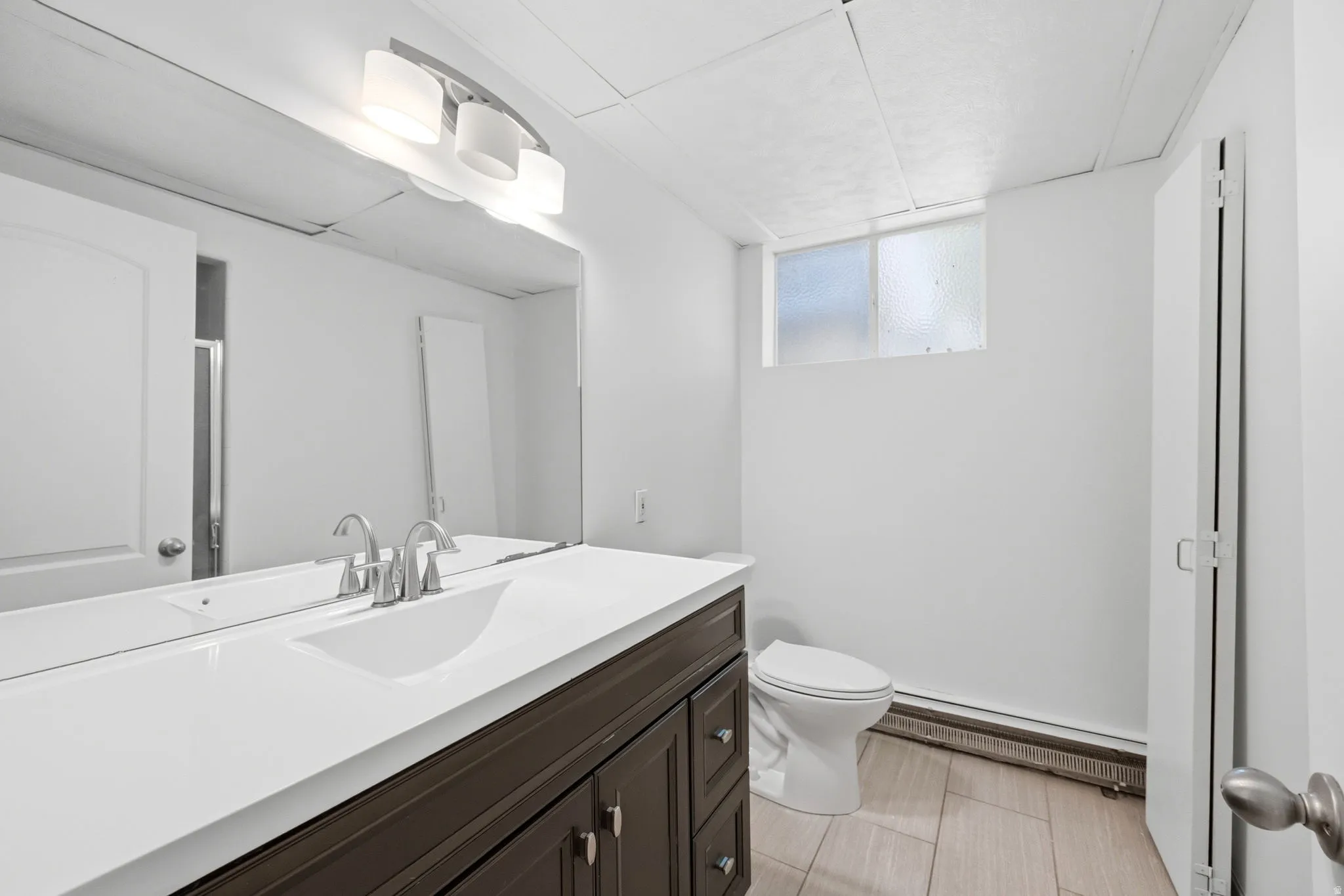 Modern bathroom vanity featuring a white countertop, undermount sink, and brushed nickel faucet