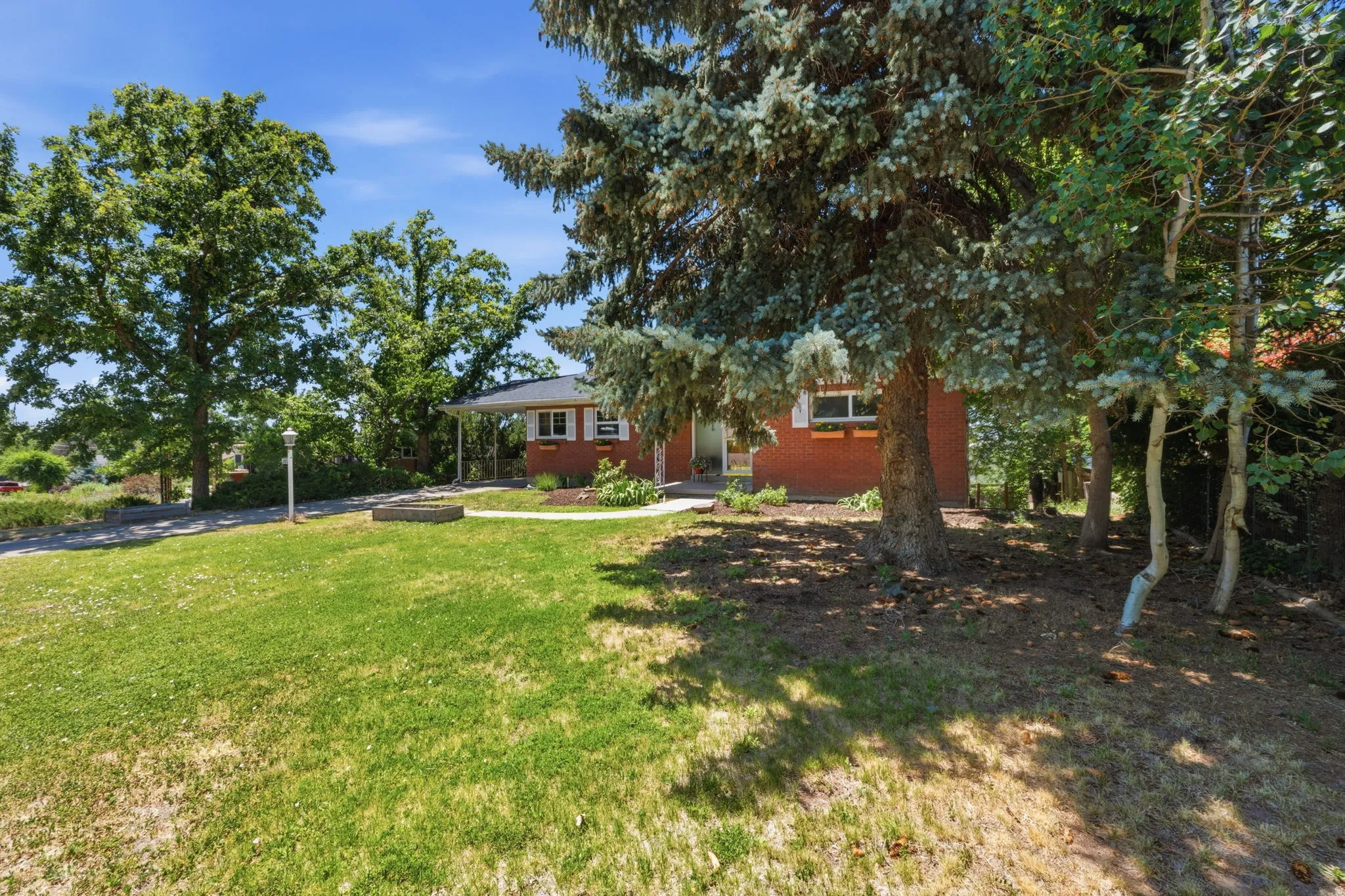 Brick exterior featuring white window trim, covered entry, and mature landscaping