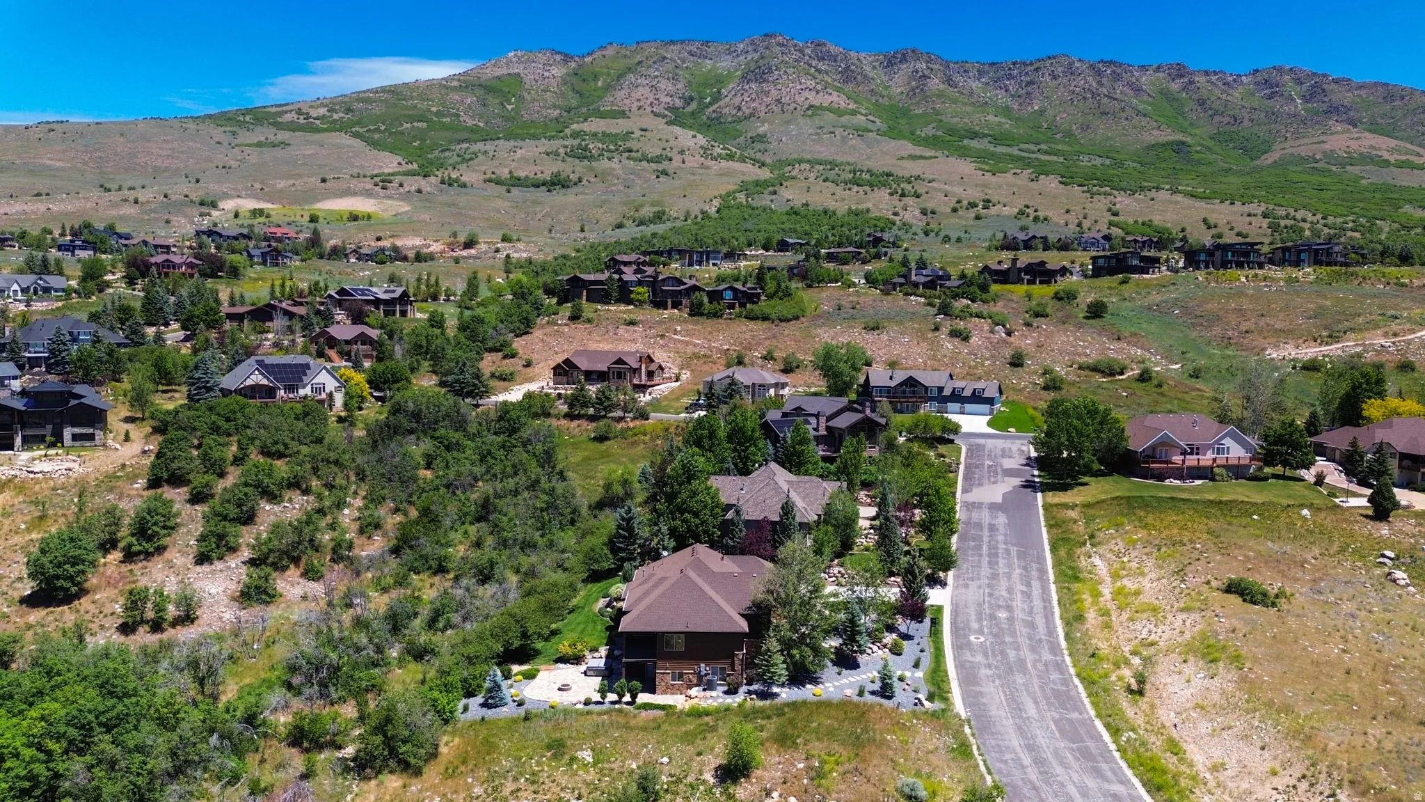 Mountainous terrain surrounding a residential area, with paved roads and multiple properties visible