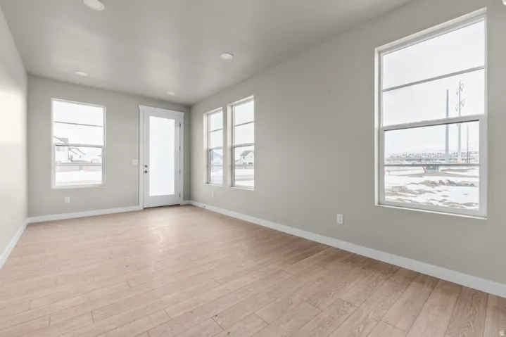 Spacious interior room featuring light wood-finish flooring, recessed lighting, and expansive windows