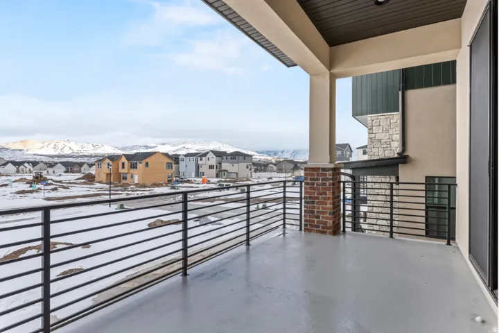 Spacious covered balcony featuring a durable concrete surface and sleek black horizontal railings