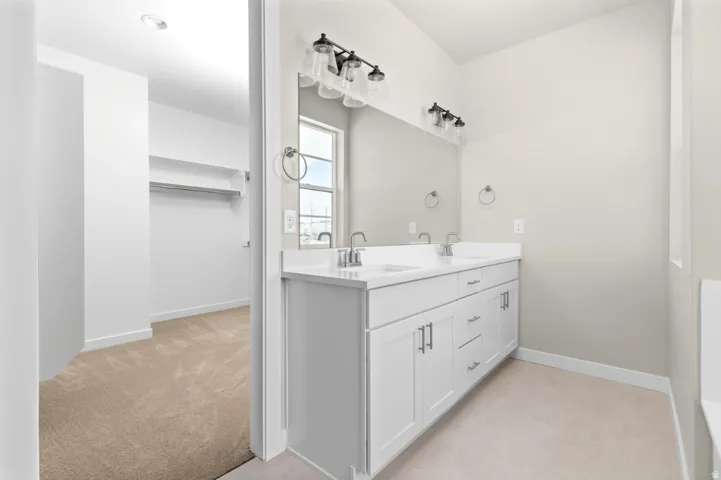 Bathroom featuring a dual vanity with white cabinetry, light-toned countertops, and brushed nickel hardware