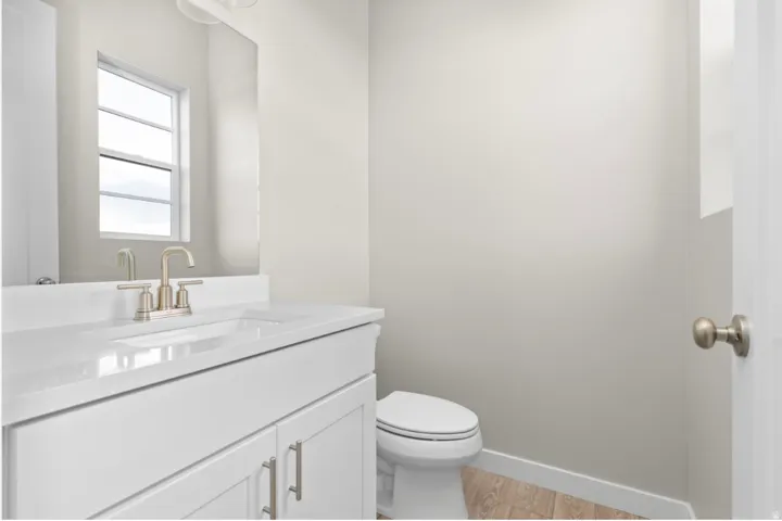 Bathroom vanity featuring a white integrated sink, brushed nickel faucet, and white shaker-style cabinetry with coordinating hardware